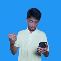 Asian man happy over hard work victory, left hand holding smart phone isolated purple background. photo