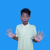 young asian man hands stop. with a serious face wearing a yellow t-shirt, isolated on a blue background photo