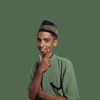 excited asian man wearing ramadan muslim clothes. pointing to copy space with side blue background. photo