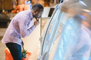 African man shopping at supermarket. Handsome guy holding shopping basket photo