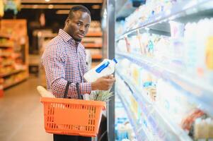 joven africano hombre comprando en tienda de comestibles sección a supermercado foto