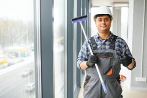 masculino profesional limpieza Servicio trabajador limpia el ventanas y tienda ventanas de un Tienda con especial equipo foto