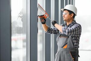 el trabajador instala un ventana marco en el habitación foto