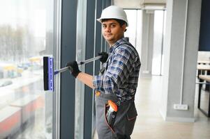 Male professional cleaning service worker in overalls cleans the windows and shop windows photo