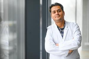 Portrait of male indian doctor on clinic corridor as background. photo