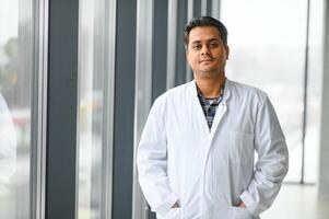 Portrait of male indian doctor on clinic corridor as background. photo