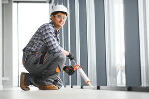 Workman in overalls installing or adjusting plastic windows photo