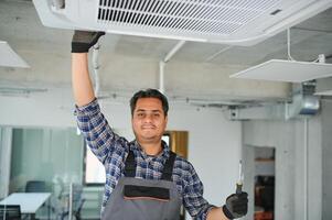 retrato de joven masculino indio técnico reparando aire acondicionador. aire acondicionador refacción. foto