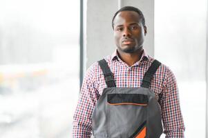 Portrait of handsome African worker or engineer in overalls and hard hat photo