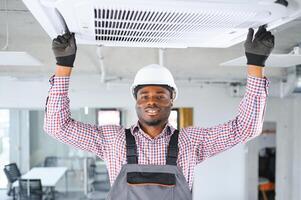 Happy Young African Male Technician Repairing Air Conditioner photo