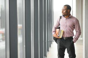 handsome college boy holding books on campus photo