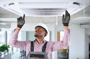 Happy Young African Male Technician Repairing Air Conditioner photo