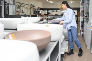 Woman choosing bathroom sink in store photo