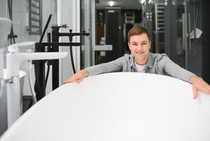 Man customer choosing ceramic bath in bathroom furniture store photo