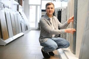 Young man choosing tiles at building market photo