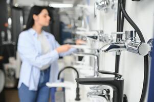 Woman inspects and chooses new kitchen or bath tap faucet at a hardware store photo