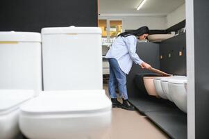 Young woman choosing bathroom toilet bowl and utensils for his home photo