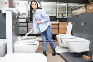 Woman choosing home toilet in store photo