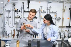 Couple choosing bathroom faucets in plumbing store photo