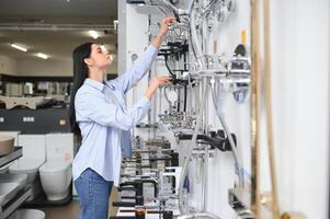 Woman inspects and chooses new kitchen or bath tap faucet at a hardware store photo