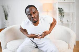 Black Man Having Stomachache Suffering From Painful Abdominal Spasm Standing Touching Aching Abdomen At Home photo