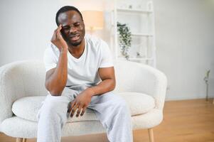 African american man stressed sitting on sofa at home photo