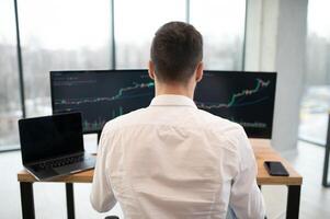 Financial Analysts and Day Traders Working on a Computers with Multi-Monitor Workstations with Real-Time Stocks, Commodities and Exchange Market Charts photo