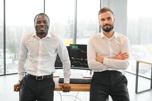 Two diverse crypto traders brokers stock exchange market investors discussing trading charts research reports growth using pc computer looking at screen analyzing invest strategy, financial risks photo