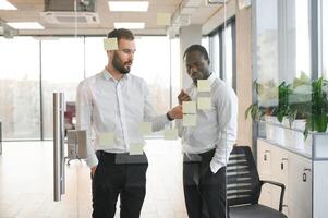 colleagues discuss and stick notes on the glass photo