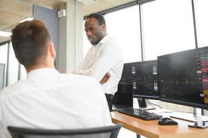 Two successful trader sitting in office, checking cryptocurrency information data on finance market graph, pointing on monitor photo