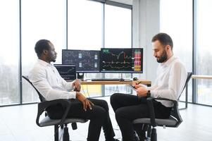 Two confident businessmen, financial analysts or investment advisers sitting at office desk photo