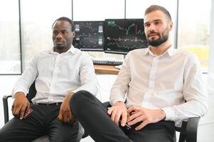 Two confident businessmen, financial analysts or investment advisers sitting at office desk photo