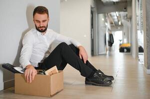 despedido frustrado hombre en traje sentado en piso en oficina foto