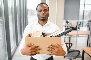 joven africano hombre despedido participación caja con personal artículos a negocio oficina foto