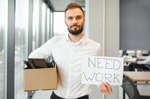 Man by dismissal. Guy lost job. Fired manager in company. Dismissal box in hands of employee. photo