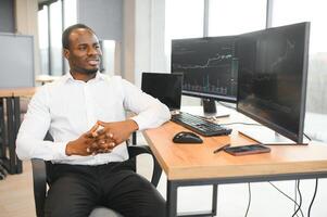 African-American broker works in office using workstation and analysis technology photo