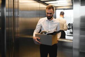 Man by dismissal. Guy lost job. Fired manager in company. Dismissal box in hands of employee. photo