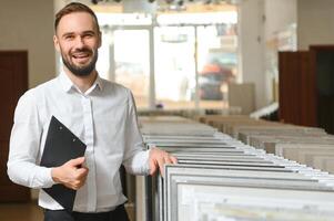 Portrait of a ceramic tile seller. The seller stands against the background of a large assortment of tiles photo