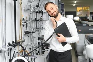 contento vendedor fontanero hombre con papel tableta en plomería tienda foto