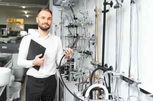 Happy salesman plumber man with paper tablet on plumbing shop photo