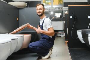 Plumber in uniform at showcase in plumbering store photo