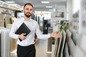 Happy salesman plumber man with paper tablet on plumbing shop photo