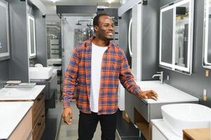 africano americano a el edificio mercado mirando para lavabo dentro su baño foto