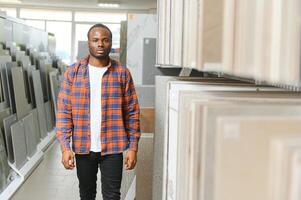 African american man customer choosing ceramic tile at building materials store photo