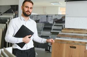 Portrait of a ceramic tile seller. The seller stands against the background of a large assortment of tiles photo