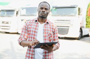 Truck driver checking shipment list while standing on parking lot of distribution warehouse photo