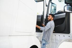 Professional indian truck driver entering his truck long vehicle. Loving his job. Transportation services. photo