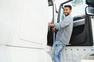 Professional indian truck driver entering his truck long vehicle. Loving his job. Transportation services. photo