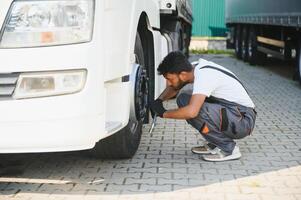 Indian Mechanic unscrews wheel truck pneumatic wrench photo