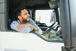 joven indio camión conductor sentado detrás direccion rueda en un cabina foto